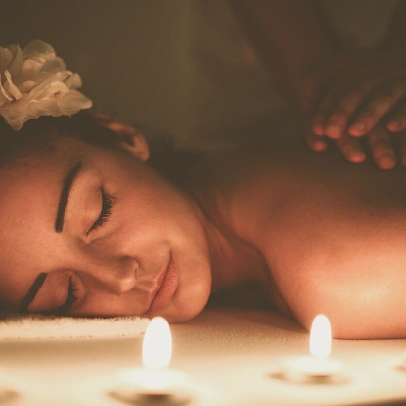 A woman laying down on her stomach with candles in front of her.