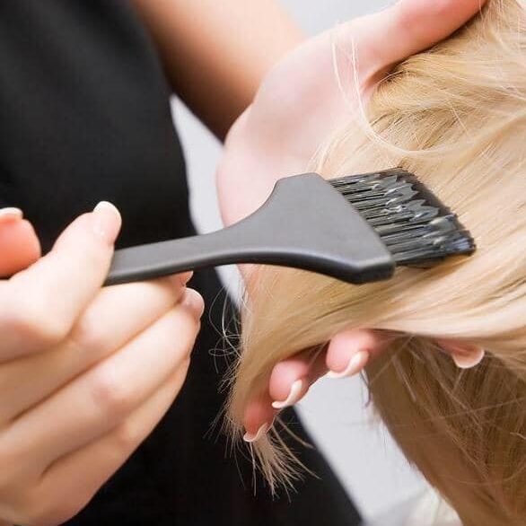 A woman getting her hair cut with a black comb.