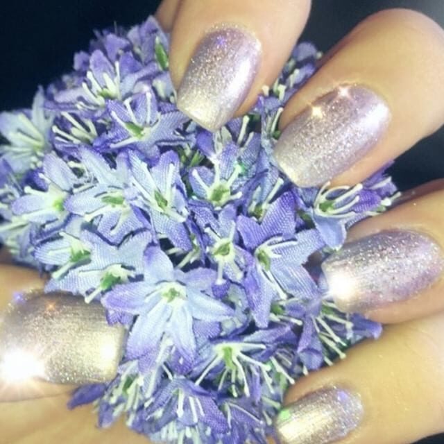 A woman holding purple flowers with silver nail polish.